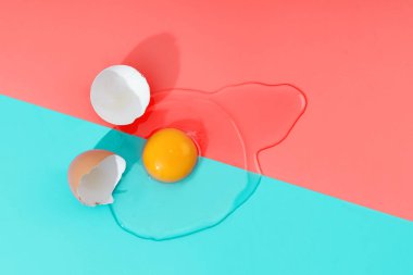 Çiğ yumurta, mercan ve turkuaz arka plandaki kırık kabuklardan kaynaklanır.