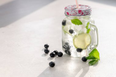 Kapaklı cam bardakta yabanmersinli mojito.