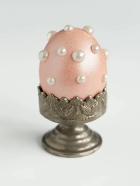 Pearl Easter egg in a vintage stand on a white background