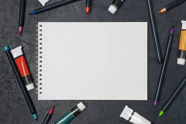 Eskiz defteri, resim ve suluboya fırçaları olan bir ressam masası.