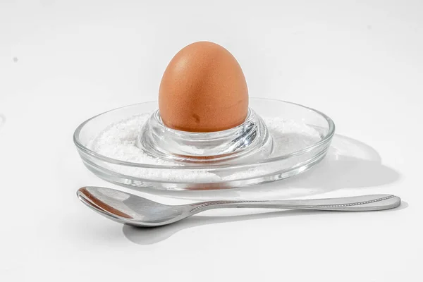 Cam tezgahta rafadan yumurta ve beyaz arka planda kaba tuz.