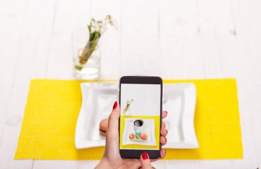 Bir kadın bir akıllı telefon ile bir restoranda yiyecek resimleri lazım