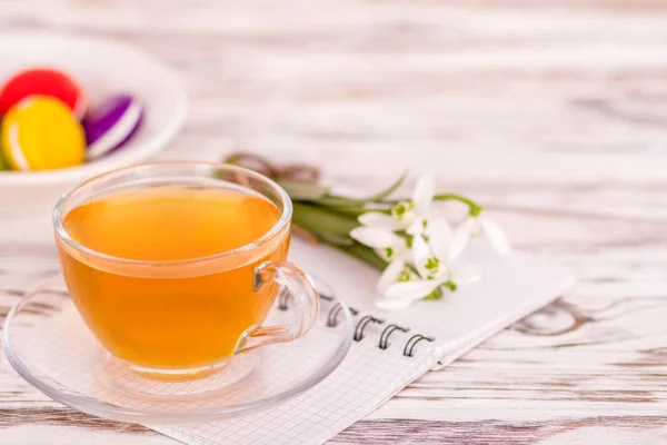 Macaroon, uma xícara de chá e flores na mesa — Fotografia de Stock
