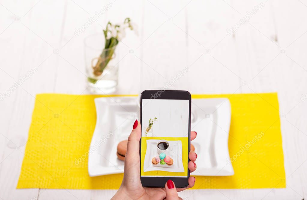 A woman with a smartphone takes pictures of food in a restaurant