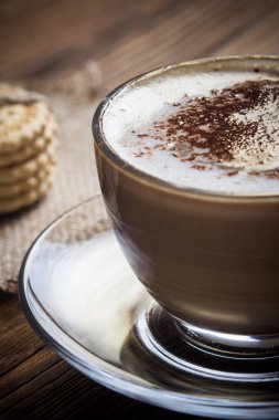 Bir fincan kahve ve bir antika ahşap masa üzerinde küçük kurabiye