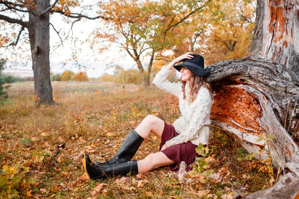 Hermosa chica en el bosque de otoño. joven con el pelo largo. Vestido con suéter y sombrero —  Fotos de Stock