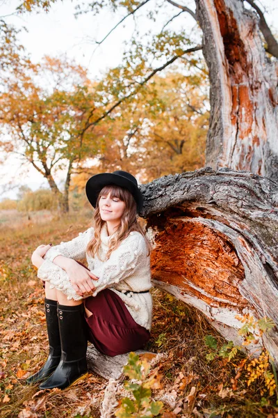 Bella ragazza nella foresta autunnale. giovane con i capelli lunghi. Vestita con maglione e cappello — Foto Stock