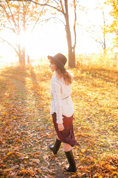 Hermosa chica en el bosque de otoño. joven con el pelo largo. Vestido con suéter y sombrero —  Fotos de Stock