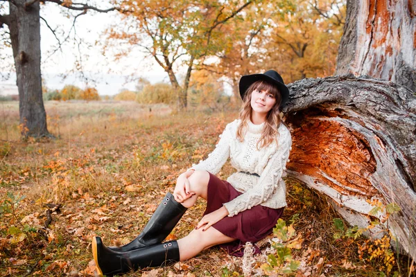 Piękna dziewczyna w lesie jesienią. Młodzi z długimi włosami. Ubrany w sweter i kapelusz — Zdjęcie stockowe