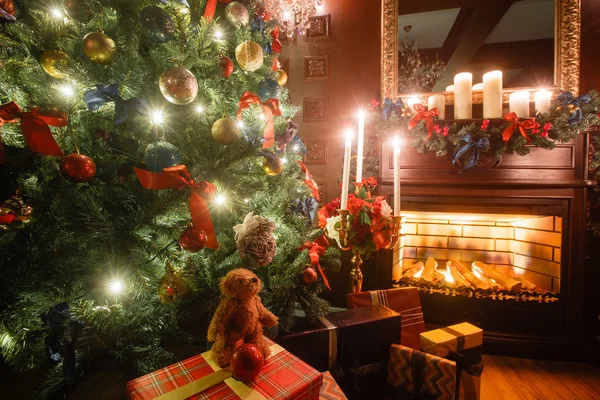 Рождественский вечер при свечах. классические апартаменты с белым камином, украшенным деревом, диваном, большими окнами и люстрой . — стоковое фото