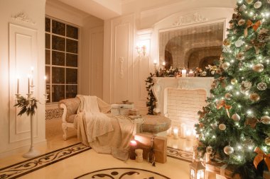 Noel akşam mum ışığında. Beyaz bir şömine, dekore edilmiş ağaç, parlak kanepe, büyük pencereler ile klasik daire