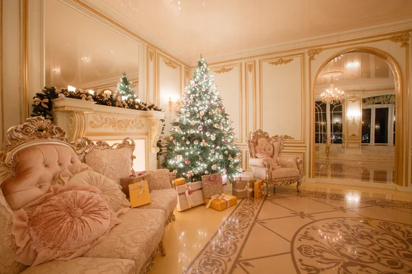 Рождественский вечер при свечах. классические апартаменты с белым камином, украшенным деревом, ярким диваном, большими окнами — стоковое фото