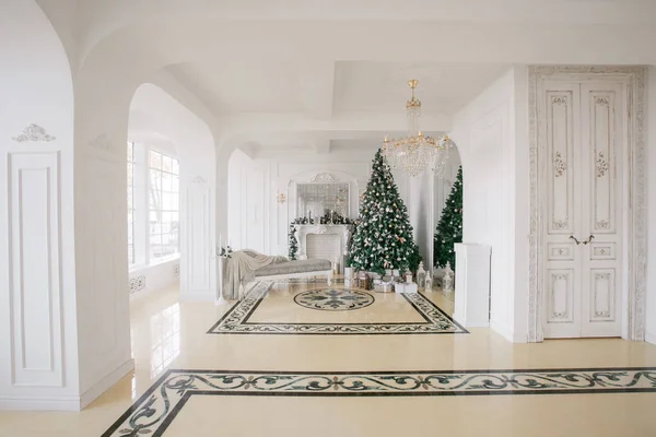 Mañana de Navidad. apartamentos de lujo clásicos con chimenea blanca, árbol decorado, sofá luminoso, grandes ventanales — Foto de Stock