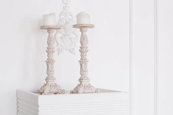 Bílé starožitné svícny se svíčkami zblízka. štukované zdi — Stock fotografie