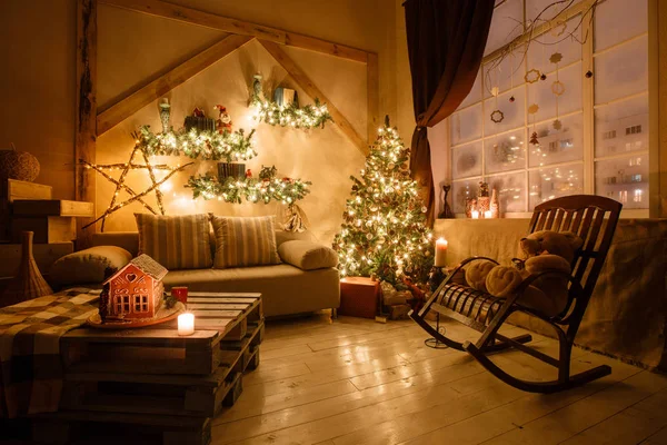 Imagen tranquila del interior de la casa moderna sala de estar decorado árbol de Navidad y regalos, sofá, mesa cubierta con manta . — Foto de Stock