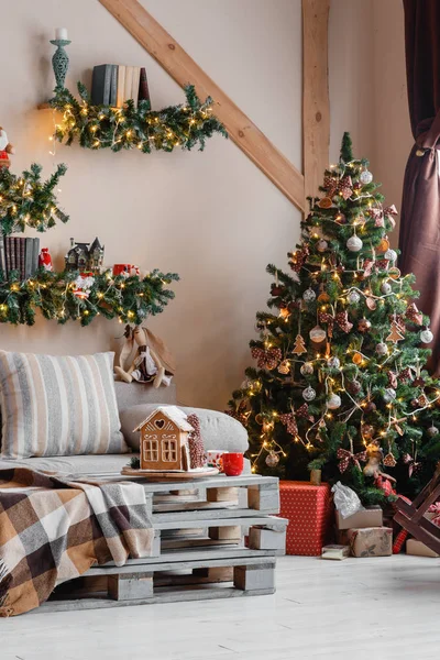 Calm image of interior modern home living room decorated christmas tree and gifts, sofa, table covered with blanket.