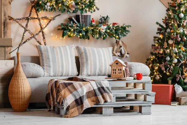 Ruhiges Bild des Interieurs modernes Zuhause Wohnzimmer dekoriert Weihnachtsbaum und Geschenke, Sofa, Tisch mit Decke bedeckt. — Stockfoto