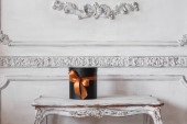 Zabalený dárek černých skříněk s pásky, jako vánoční dárek na stůl luxusní bílé zdi basreliéf štukové lišty příslušenstvím prvky návrhu