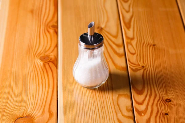 Стакан металлический с гранулированным сахаром на деревянном столе — стоковое фото