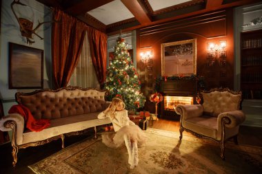 Noel akşamı. Beyaz bir şömine, genç güzel sarışın kadın kahve klasik daire ile süslenmiş ağaç.