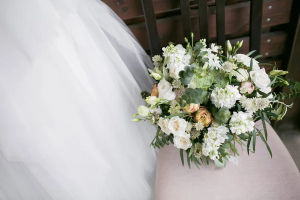 Букет невесты. Невесты. Белые цветы и зелень, украшенные шелковой лентой, лежат на винтажном деревянном стуле — стоковое фото