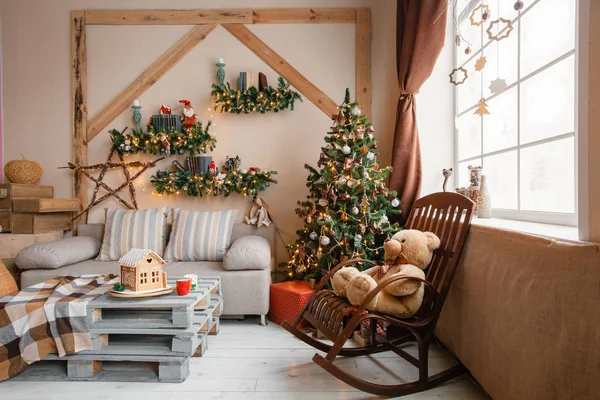 Imagen tranquila del interior de la casa moderna sala de estar decorado árbol de Navidad y regalos, sofá, mesa cubierta con manta . — Foto de Stock