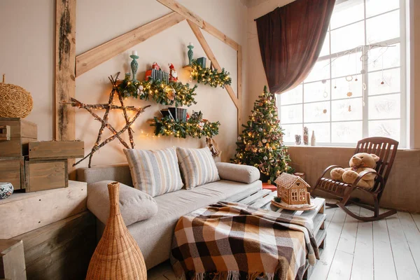 Imagen tranquila del interior de la casa moderna sala de estar decorado árbol de Navidad y regalos, sofá, mesa cubierta con manta . — Foto de Stock