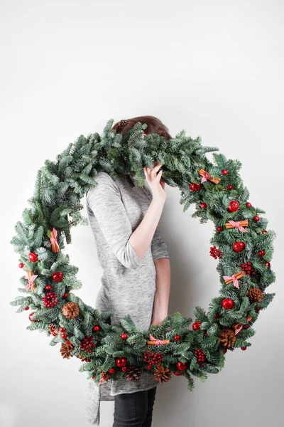 Młoda kobieta gospodarstwa Boże Narodzenie wieniec duży w ręce w światło, świąt, wiejskiego motywu, zdobiące — Zdjęcie stockowe