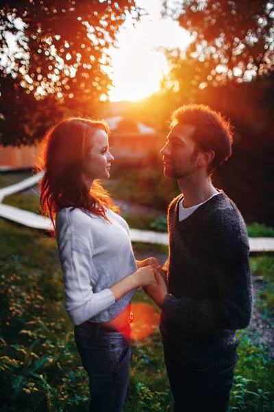 Estilo de vida ao ar livre retrato de jovem casal apaixonado de pé no parque velho na rua atrás do pôr do sol — Fotografia de Stock