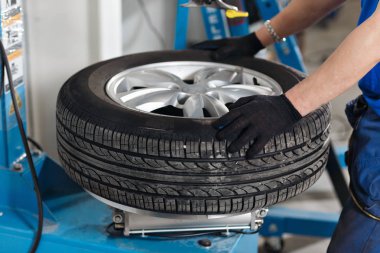 Makinist araba lastiği closeup kaldırır. Lastik tekerlekli diskten kaldırmak için makine
