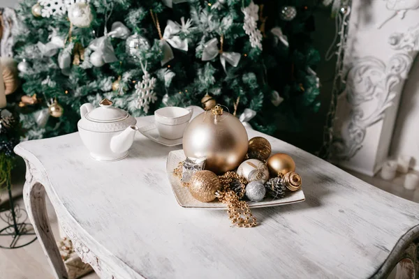 Χριστουγεννιάτικα διακοσμητικά στο τραπέζι το φόντο μιας εστίας διακοσμημένα με κλαδιά ερυθρελάτη και γιρλάντα. — Φωτογραφία Αρχείου