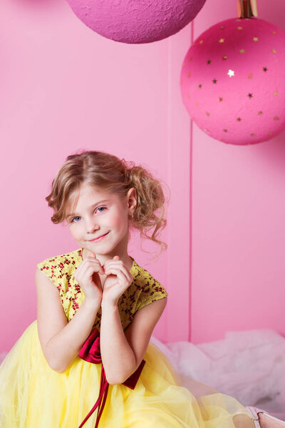 Валентина сердце, чтобы сделать ваши пальцы. Прелестная девочка 6 лет в желтом платье. Ребенок в комнате из розового кварца украшен праздником
.