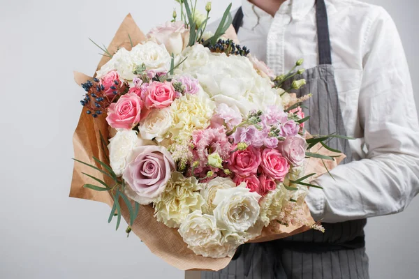 Piękny bukiet z różnych kwiatów w ręku młodego człowieka. kolor kolorowy kwiat mix. Odzież robocza w białej koszuli i szary fartuch — Zdjęcie stockowe