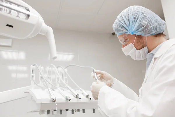 El dentista se inclinó sobre el paciente en la silla de la clínica. Médico con máscara y herramientas — Foto de Stock