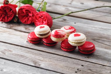 Kırmızı macaroons tatlılar ve gül ahşap arka plan üzerinde. tatlı kahvaltı Sevgililer günü için. kopya alanı