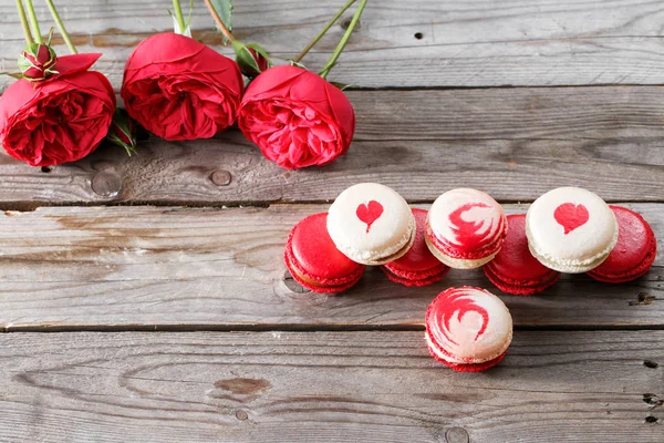 Red macaroons desserts and roses on wooden background. dessert for breakfast on Valentines Day. copy space — Stock Photo, Image