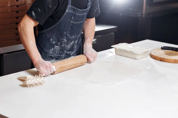 Викиньте тісто. крупним планом рука кухаря пекарні в уніформі синього фартуха готують піцу на кухні — стокове фото