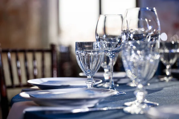 Boda. Banquete. Las sillas y la mesa redonda para los huéspedes, servidas con cubiertos y vajilla y cubiertas con un mantel azul . — Foto de Stock