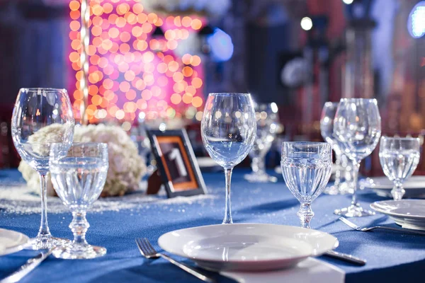 Boda. Banquete. Las sillas y la mesa para los huéspedes, servidas con cubiertos y vajilla y cubiertas con un mantel azul . — Foto de Stock