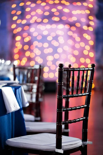 Boda. Banquete. Las sillas y la mesa para los huéspedes, servidas con cubiertos y vajilla y cubiertas con un mantel azul . — Foto de Stock