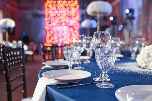 Boda. Banquete. Las sillas y la mesa para los huéspedes, servidas con cubiertos y vajilla y cubiertas con un mantel azul . — Foto de Stock