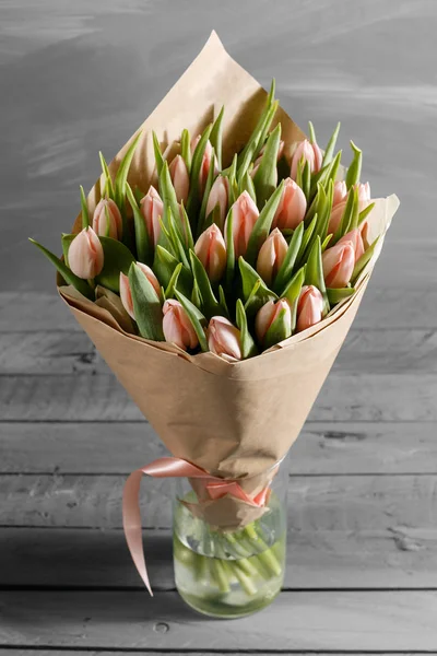 Bouquet de tulipes roses dans un paquet de papier kraft, sur fond wodden gris — Photo