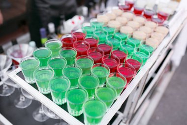 Çeşitli mobil çubuğu üstündeki satırda duran küçük bardaklarda renkli yeşil kırmızı ve beyaz güzel alkol tatlı Shooter çekim kokteyl taze içecek