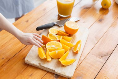 Childs'ın el meyve için ulaşır. dilimlenmiş portakal ahşap kesme tahtası üzerinde. Sağlıklı ve lezzetli kahvaltı