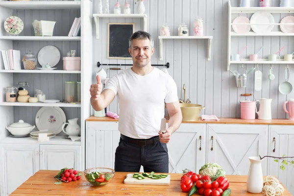 Medelålders atlet, skär grönsaker sallad på gurka och tomat. Vegetarisk mat — Stockfoto