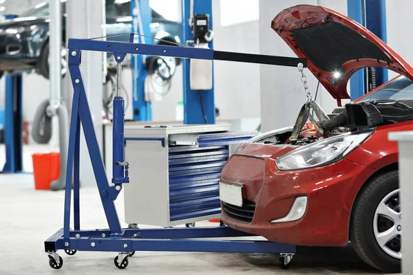 Mecánico de automóviles una grúa retiró el motor del coche. reparación de automóviles en la tienda de automóviles — Foto de Stock