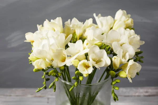 Fleurs blanches freesia dans un vase décoratif sur un fond de mur gris — Photo