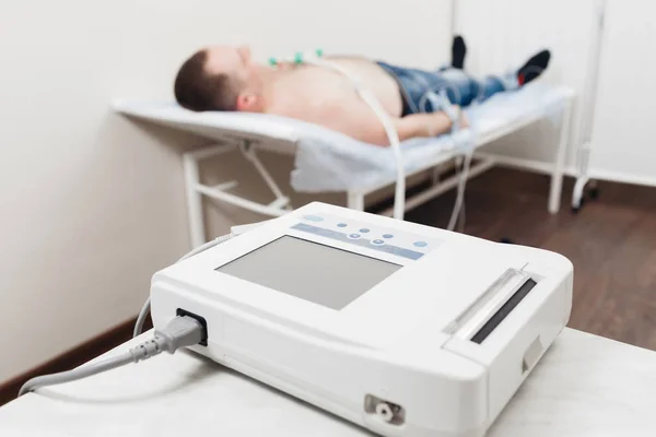 Apparaat of apparaat de maateenheid van de elektrocardiogram in een kantoor van de artsen. Mannelijke patiënt met elektrocardiogram Ecg in ziekenhuis. selectieve aandacht — Stockfoto