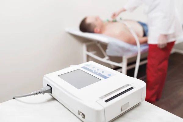 apparatus or device the unit of measurement of the electrocardiogram in a doctors office. Male patient having ECG electrocardiogram in hospital. selective focus