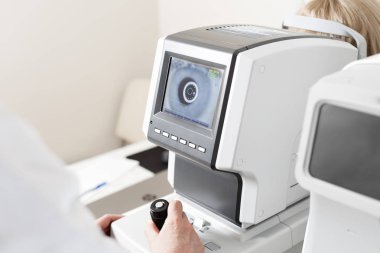 Optalmoloji kliniğinde göz testi makinesine bakan kadınlar